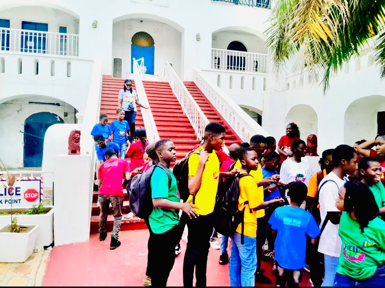 Pupils and staff gathered on the bright red stairs at Humble Dream Montessori School
