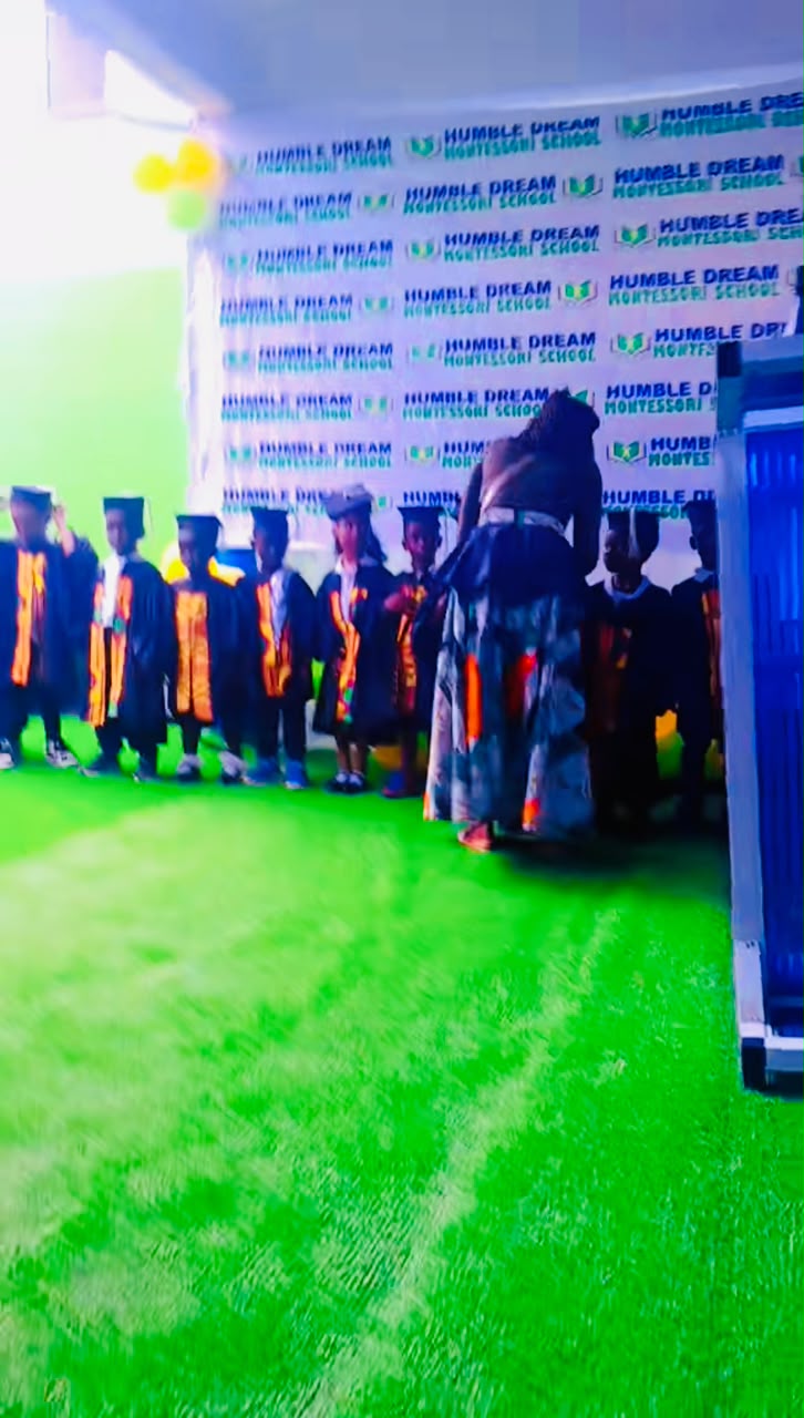 A teacher with graduating pupils in caps and gowns at Humble Dream Montessori School